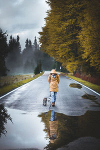 Young woman walking by cat on street during rainy season