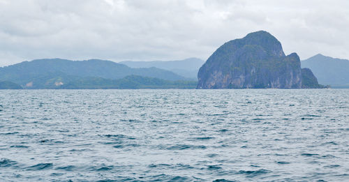 Scenic view of sea by mountains against sky