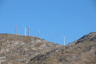 Low angle view of windmill on mountain against clear blue sky