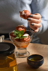 Midsection of woman holding strawberry in glass on table