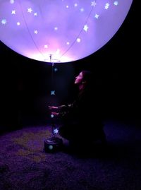 Side view of woman with illuminated lantern in darkroom