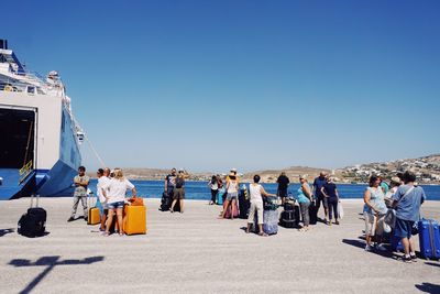 People on beach against clear blue sky