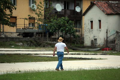 Rear view of man walking on footpath against buildings