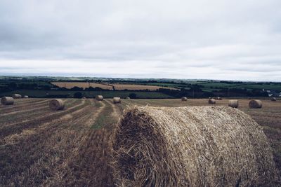 Hay bales on field against sky