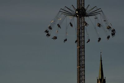 Low angle view of chain swing ride against sky