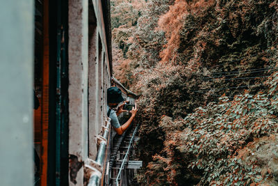 Man standing by abandoned window in forest