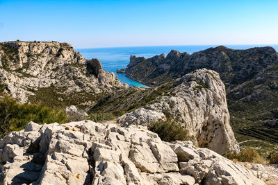 Scenic view of rocky mountains by sea against clear sky