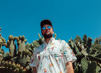 Low angle view of young man standing against clear blue sky