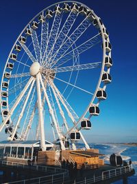 Low angle view of ferris wheel against clear blue sky