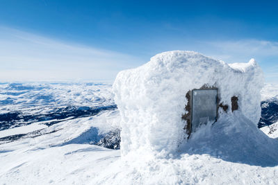 Snow covered hut on mountain against sky