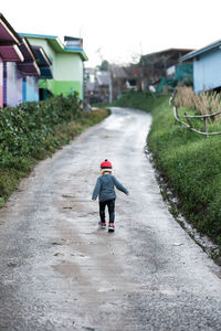 Rear view of toddler running on single lane road in village