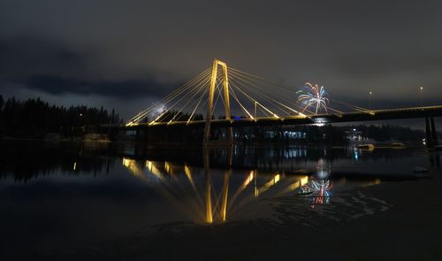 Illuminated bridge over river against sky at night