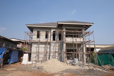 Abandoned building by construction site against sky