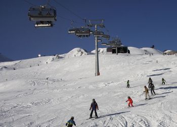 People skiing on snow covered mountain against clear sky