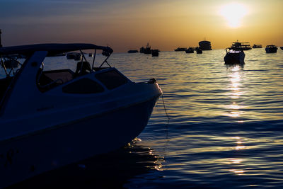 Boat moored on sea against sky during sunset