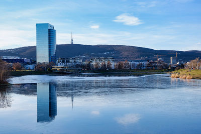 Buildings by lake against sky in city