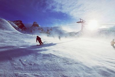 People skiing on snowcapped mountain against sky