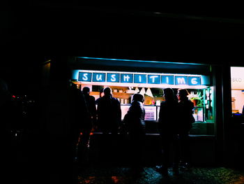 People walking on illuminated road at night