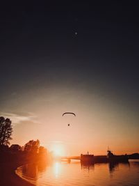 Silhouette people by boats against sky during sunset