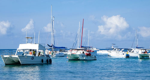 Sailboats moored in sea against sky