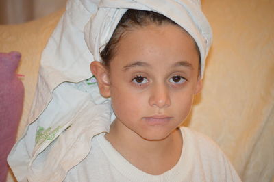 Close-up portrait of cute girl wrapped in towel at home