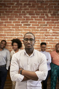 Portrait of young man standing against brick wall