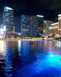 Illuminated buildings by swimming pool at night