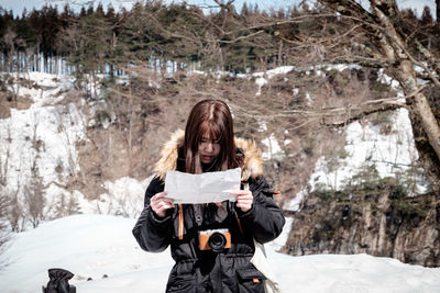 Full length of young woman photographing in winter