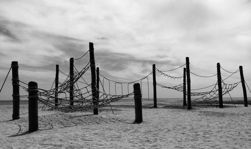 Wooden posts on beach against sky