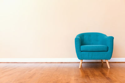 Empty chair against blue wall at home