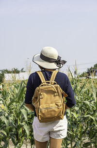 Rear view of woman wearing hat standing on field