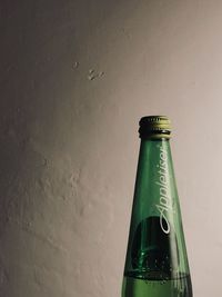 Close-up of beer bottle against wall