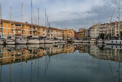 Sailboats moored in harbor against buildings in city