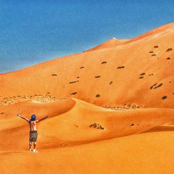 Man standing on sand dune in desert against sky