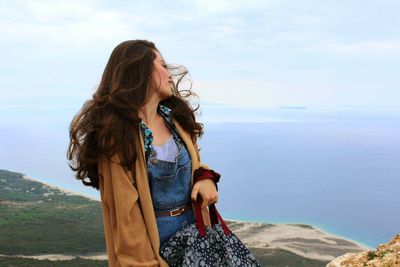 Young woman at beach against sky