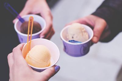 Close-up of hand holding ice creams in containers on footpath