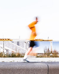 Blurred motion of man running against clear sky