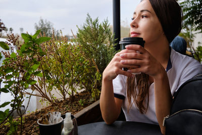Thoughtful young adult attractive caucasian woman drinks coffee at cafe