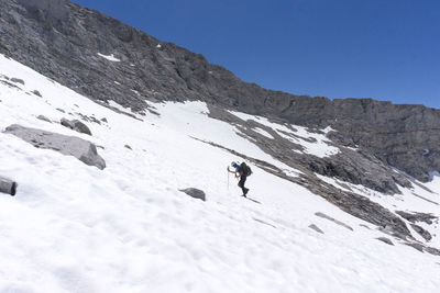 Man skiing on snowcapped mountain against clear sky