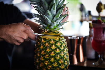 Cropped image of man holding fruit on table