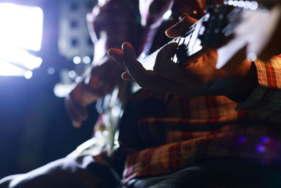 Close-up midsection of man playing guitar in music concert