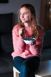 Beautiful young woman sitting on sofa at home