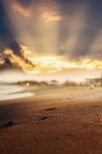 Surface level of beach against sky during sunset