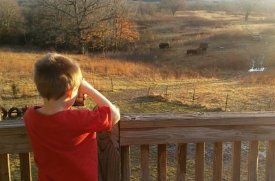 Rear view of boy photographing field