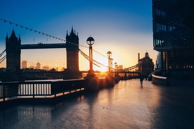 Bridge over river in city at sunset