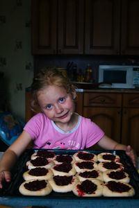 A girl prepares pies with lingonberries in the kitchen