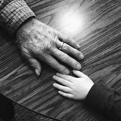 Cropped hands of grandfather and grandchild on table