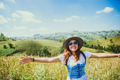 Young woman smiling on field against sky