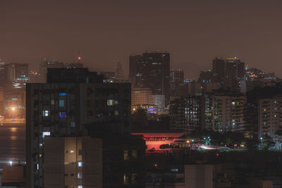 Illuminated buildings in city against sky at night