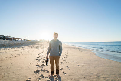 Portrait of man standing on beach against clear sky
